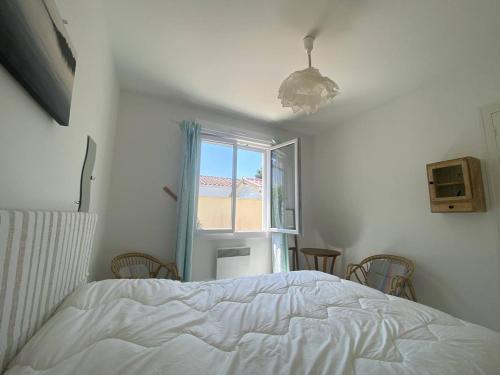 - une chambre avec un lit et une fenêtre avec des chaises dans l'établissement Villa T4 à Vaux-sur-Mer, proche plages, jardin et terrasses - FR-1-738-42, à Vaux-sur-Mer