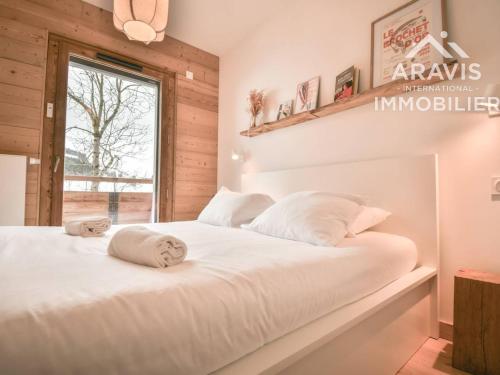 une chambre avec un lit avec des draps blancs et une fenêtre dans l'établissement Appartement moderne avec vue sur les pistes et cuisine équipée - FR-1-391-201, au Grand-Bornand