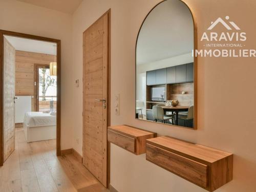 un miroir sur le mur d'une pièce avec une table dans l'établissement Appartement moderne avec vue sur les pistes et cuisine équipée - FR-1-391-201, au Grand-Bornand
