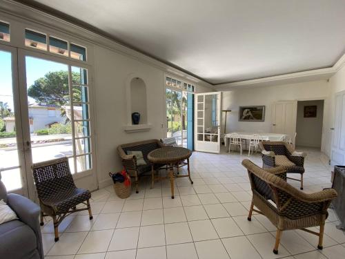 un salon avec des chaises, une table et des fenêtres dans l'établissement Villa charmante à Cavalaire avec climatisation et parking, proche port et plage - FR-1-100-346, à Cavalaire-sur-Mer
