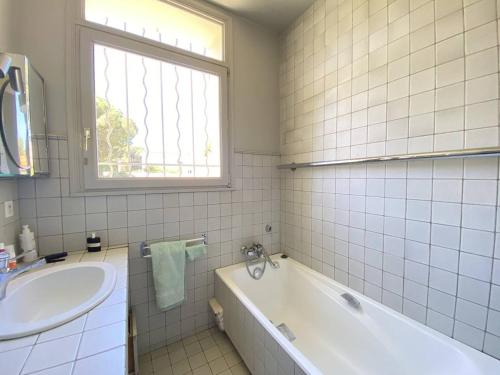 une salle de bain blanche avec une baignoire et un lavabo dans l'établissement Villa charmante à Cavalaire avec climatisation et parking, proche port et plage - FR-1-100-346, à Cavalaire-sur-Mer