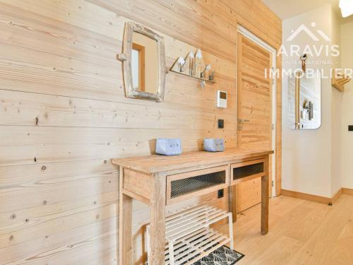 Cette chambre est dotée d'un mur en bois avec une table et un miroir. dans l'établissement Chalet confortable avec balcon, garage et vue sur les pistes - FR-1-391-202, au Grand-Bornand