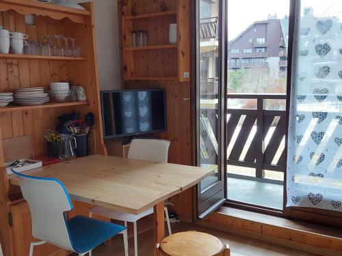 - une table et des chaises en bois dans une chambre avec fenêtre dans l'établissement Appartement calme avec balcon à Chamonix, parking et wifi inclus - FR-1-517-70, à Chamonix-Mont-Blanc