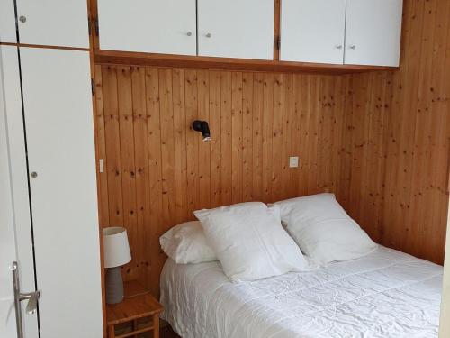 - une chambre dotée d'un lit avec des murs en bois et des oreillers blancs dans l'établissement Appartement calme avec balcon à Chamonix, parking et wifi inclus - FR-1-517-70, à Chamonix-Mont-Blanc