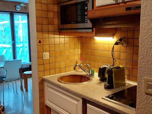 un comptoir de cuisine avec un évier et un micro-ondes dans l'établissement Appartement calme avec balcon à Chamonix, parking et wifi inclus - FR-1-517-70, à Chamonix-Mont-Blanc