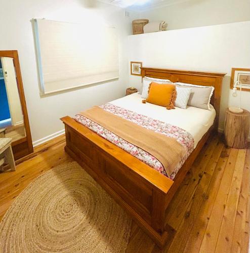a bedroom with a large wooden bed with a window at York Huon Farmhouse in Lower Botobolar