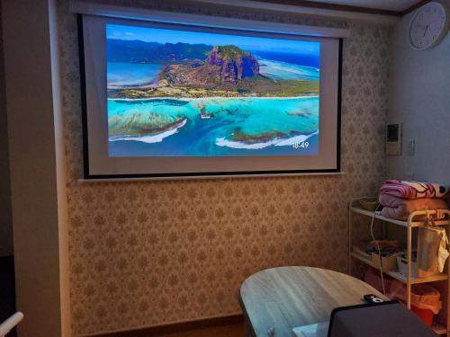 a flat screen tv hanging on a wall at Takaraboshi room 301 Sannomiya 10 min in Kobe