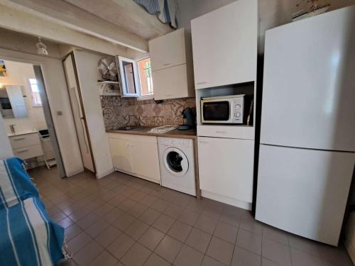 une cuisine avec des armoires blanches et un réfrigérateur blanc dans l'établissement Appartement avec loggia et parking privé, proche de la plage - FR-1-326-842, à Marseillan