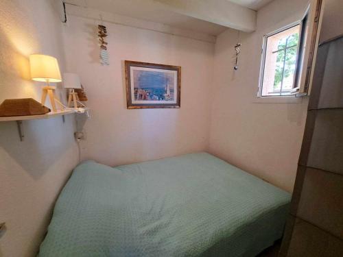 une petite chambre avec un lit et une fenêtre dans l'établissement Appartement avec loggia et parking privé, proche de la plage - FR-1-326-842, à Marseillan
