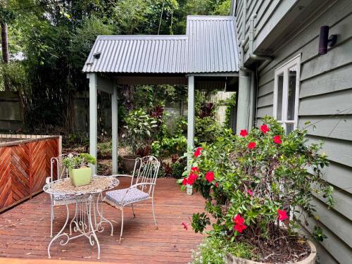 a patio with two chairs and a table and flowers at Misty Valley Cottage in Mapleton