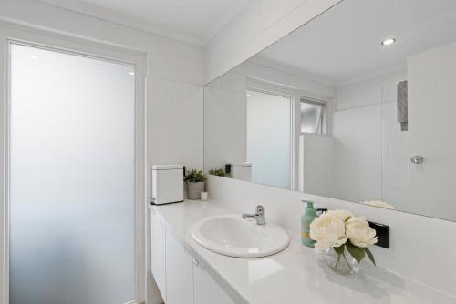 a white bathroom with a sink and a mirror at 60 Seagull Ave Chiton - Linen Included in Hayborough