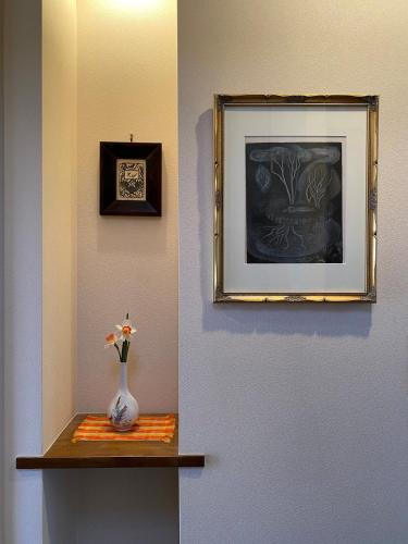a vase on a shelf with a picture on the wall at 湘南ソラル2nd 最大8名一棟貸切 犬OK 駅近 ビーチ近 観光に最適 in Ninomiya
