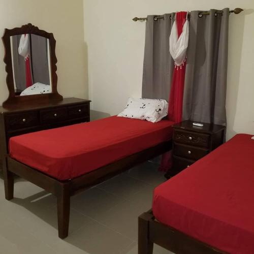 two beds in a room with a mirror and a mirror at Savannah's Place, Drax Hall Manor - FREE Wifi, AC in Steer Town