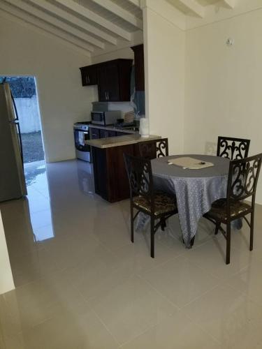 a kitchen with a table and chairs in a room at Savannah's Place, Drax Hall Manor - FREE Wifi, AC in Steer Town