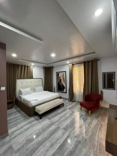 IkoyiにあるDominion Apartmentのベッドと赤い椅子のある寝室