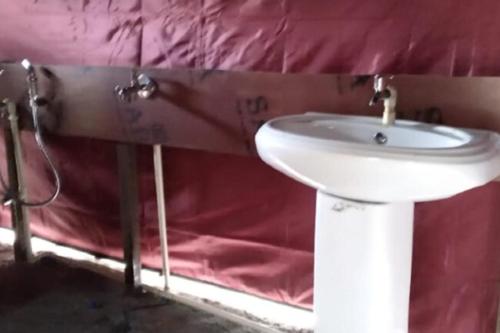 a bathroom with a white sink in a red wall at Camping at Serene Chopta in Sari