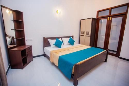 a bedroom with a bed with blue pillows at Sunset View Galle in Pedinnoruwa