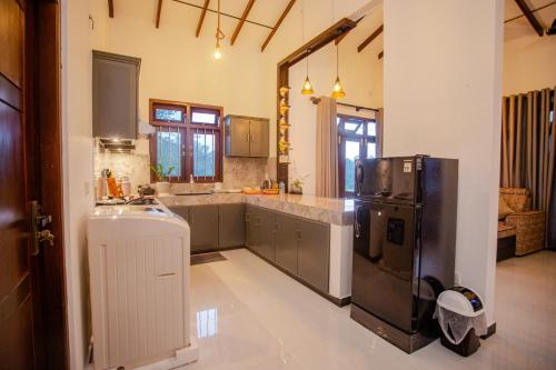 a large kitchen with a refrigerator and a sink at Sunset View Galle in Pedinnoruwa