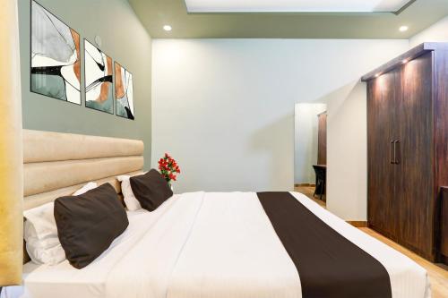a bedroom with a large white bed with black pillows at Super Hotel O Gomti Nagar Vigyan khand in Lucknow