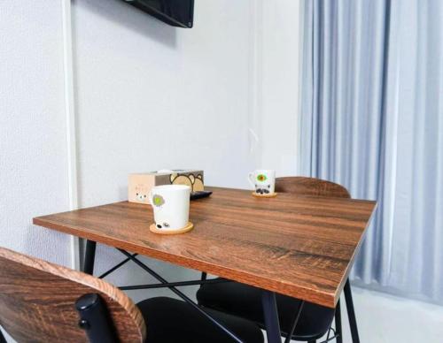 a wooden table with two coffee mugs on it at F House Os Residence S2 in Osaka