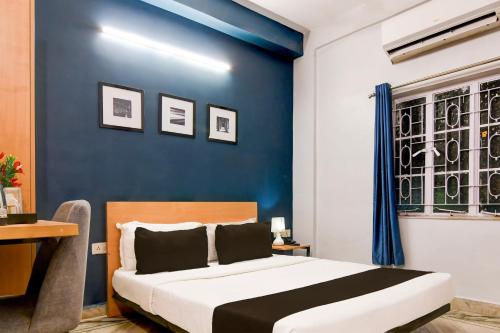 a bedroom with a blue wall and a bed at Super Hotel O Picnic Garden formerly Amaris Stay in Kolkata