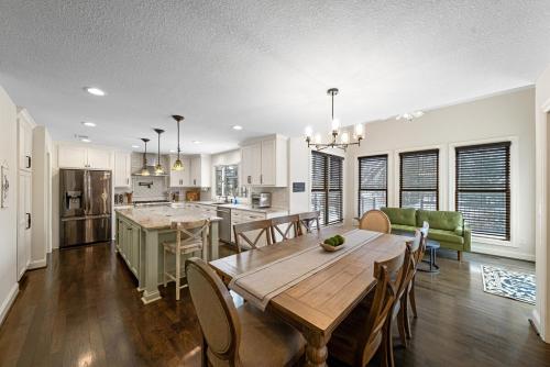 a kitchen and living room with a wooden table and chairs at EPIC Group Stay Big Gameroom Bar Arcade Playroom in Olathe