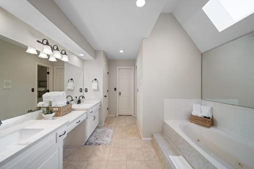 a white bathroom with two sinks and a large mirror at EPIC Group Stay Big Gameroom Bar Arcade Playroom in Olathe
