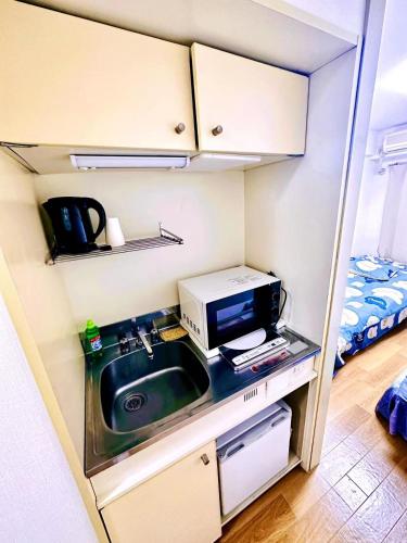a small kitchen with a sink and a microwave at West Shinjuku Entire House with 2beds in Tokyo