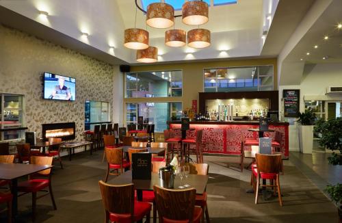 un restaurante con mesas y sillas y un bar en The Garden Hotel en Christchurch