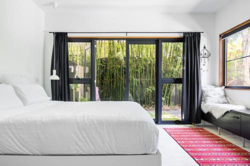 Un dormitorio con una cama blanca y una ventana grande. en StayByronBay - The Little French Salon de la Sirène and Scandinavian Simplicity Byron Bay, en Byron Bay