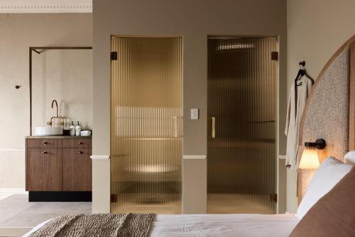 a glass shower in a bedroom with a bed at Empire Hotel in Sydney