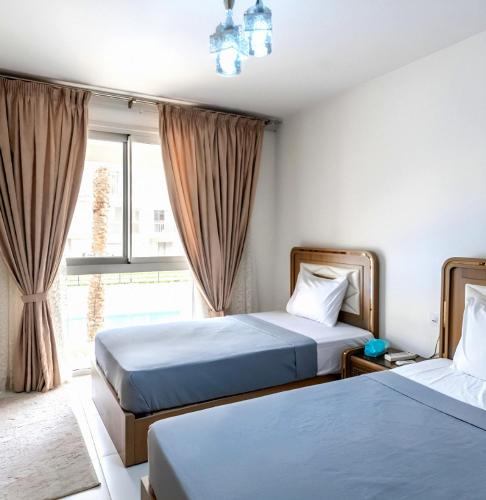 zwei Betten in einem Zimmer mit Fenster in der Unterkunft Marassi Marina VIP in El-Alamein