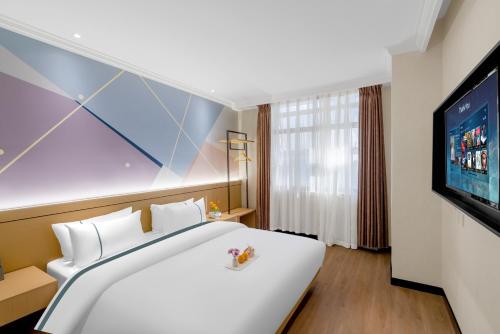 昆明Junao Hotel Nanping Pedestrian Street Branch的一间配有大床和电视的酒店房间