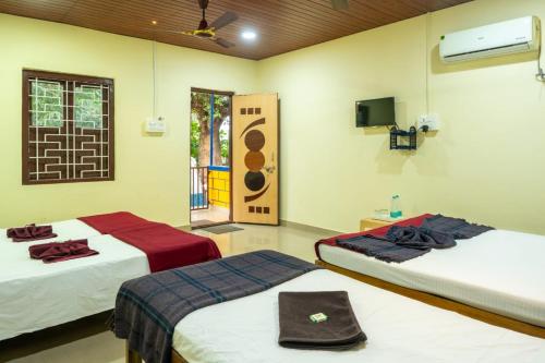 a room with two beds and a television in it at New river side cottages in Dandeli