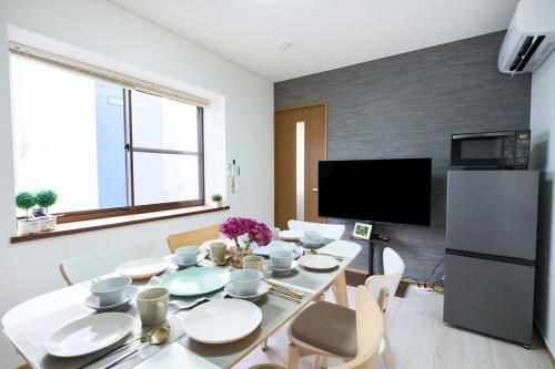 a dining room with a table with chairs and a television at KANAKO GUEST HOUSE 1号館 osaka in Osaka