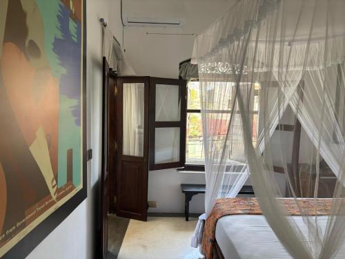 a bedroom with a bed with curtains and a window at Prince of Galle (inside the Fort) in Galle