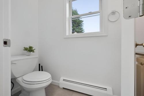 a white bathroom with a toilet and a window at Peaceful Paradise , Dream Holiday Home in Woodridge in Mountain Dale
