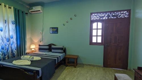 a room with two beds and a door and a window at Lake view nest in Tangalle