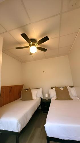 two beds in a room with a ceiling fan at Peaceful Paradise , Dream Holiday Home in Woodridge in Mountain Dale
