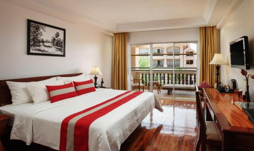 a bedroom with a bed and a desk and a window at Hotel Somadevi Angkor Resort & Spa in Siem Reap