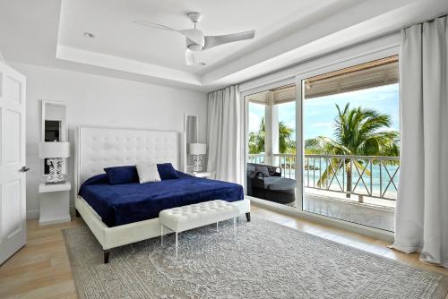 a bedroom with a blue bed and a balcony at White House - Exclusive Luxury Beachfront Villa - Private White Sand Beach in Nassau