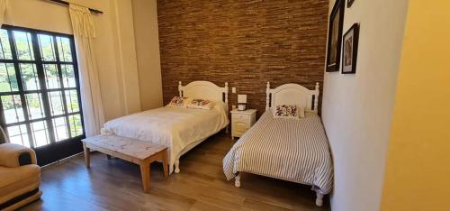 a bedroom with two beds and a brick wall at Hotel El Encuentro in Tochimpa