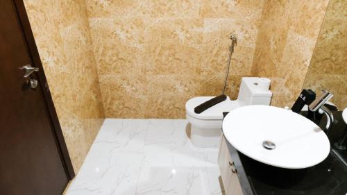 a bathroom with a white toilet and a sink at Nice and Relax 1BR at Grand Sungkono Lagoon Apartment By Travelio in Surabaya