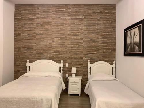 two beds in a room with a brick wall at Hotel El Encuentro in Tochimpa