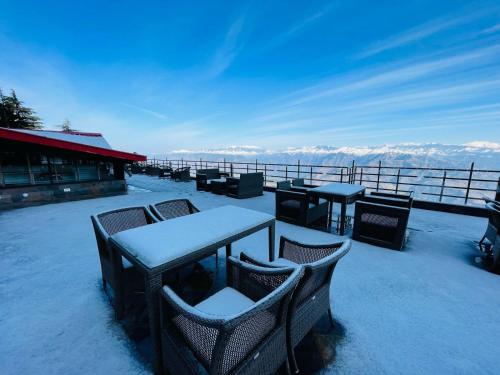 a deck with tables and chairs covered in snow at Regenta Place Dalhousie at Mall Road in Dalhousie