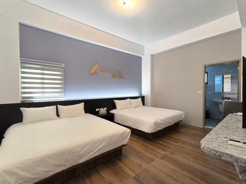 a hotel room with two beds and a bathroom at 翹班旅行民宿 in Magong