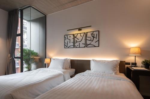 a bedroom with two beds and a window at Norma Hotel Sathorn - Formerly T2 Residence Sathorn in Bangkok
