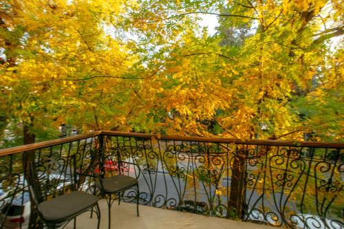 a balcony with two chairs and a tree with yellow leaves at Theatrum Hotel Baku in Baku
