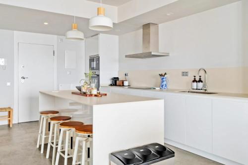a kitchen with white cabinets and bar stools at Sea view apartments with Year-Round Open Pool in Manilva