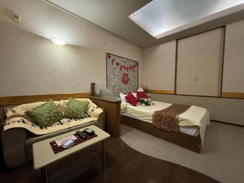 a hotel room with two beds and a couch at ホテル オリエント in Takasaki